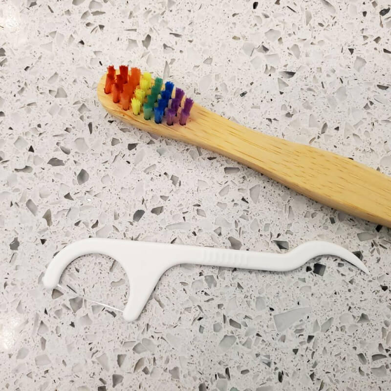 PLA dental floss pick next to a child's bamboo toothbrush